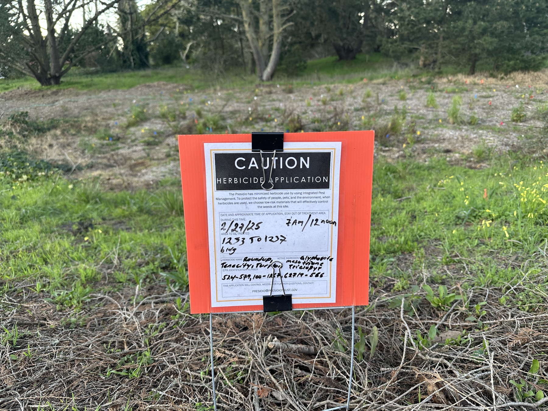 Caution herbicide application sign listing Roundup, Tenacity, and Turflon near buildings 1233 to 1237 in the Presidio