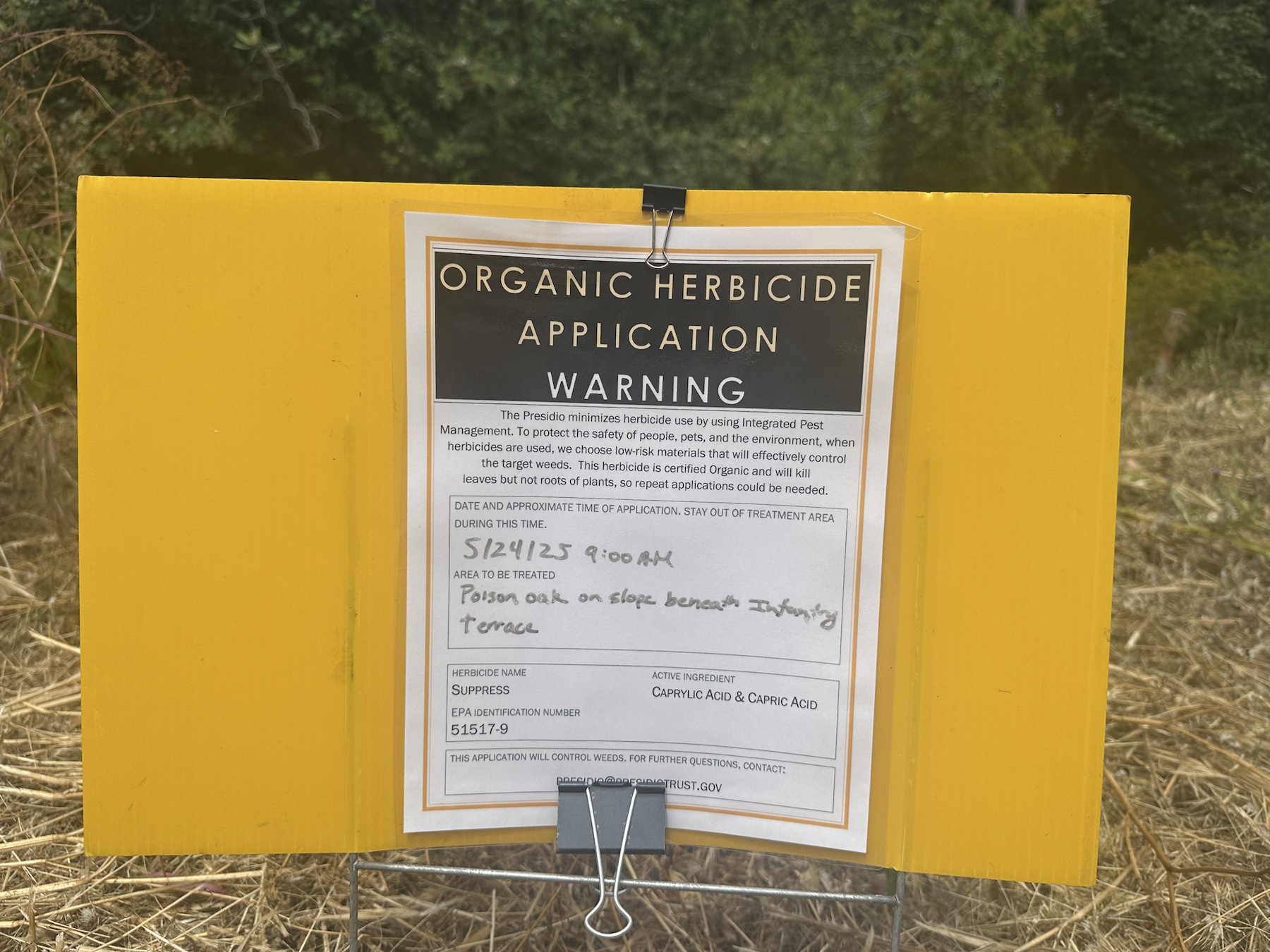 Organic herbicide application warning sign listing Suppress for poison oak beneath Infantry Terrace