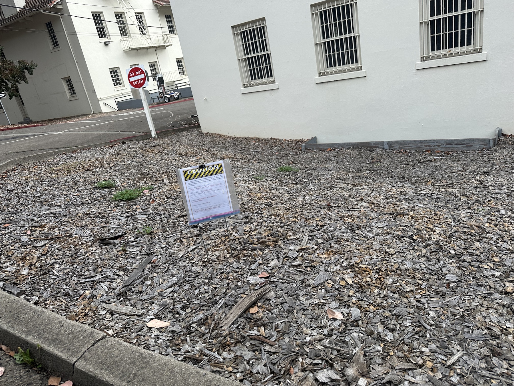 Wide view of Cheetah Pro herbicide sign in landscape bed near Ralston Ave buildings