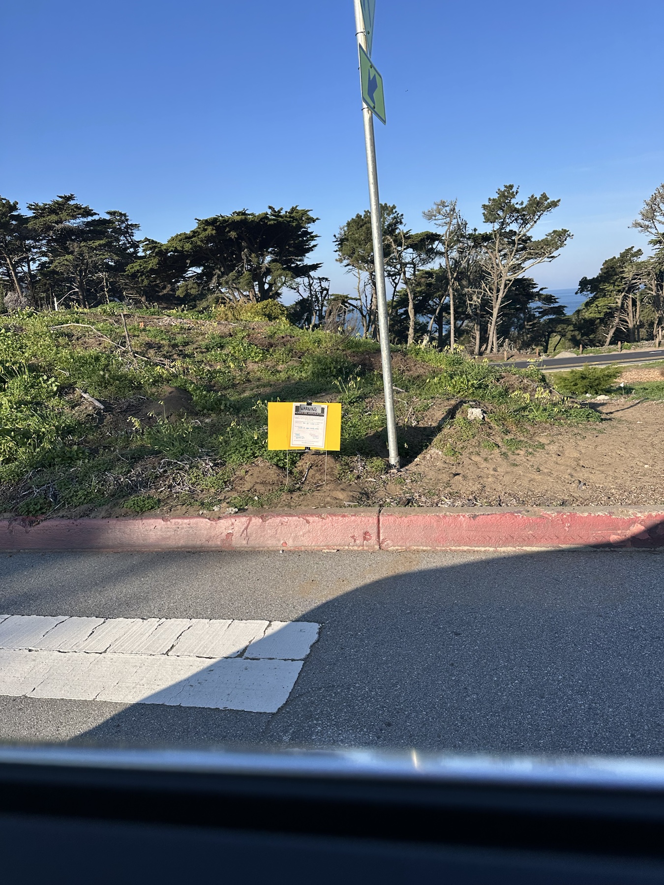 Warning herbicide application sign posted in a sandy roadside planting area near Lincoln Boulevard
