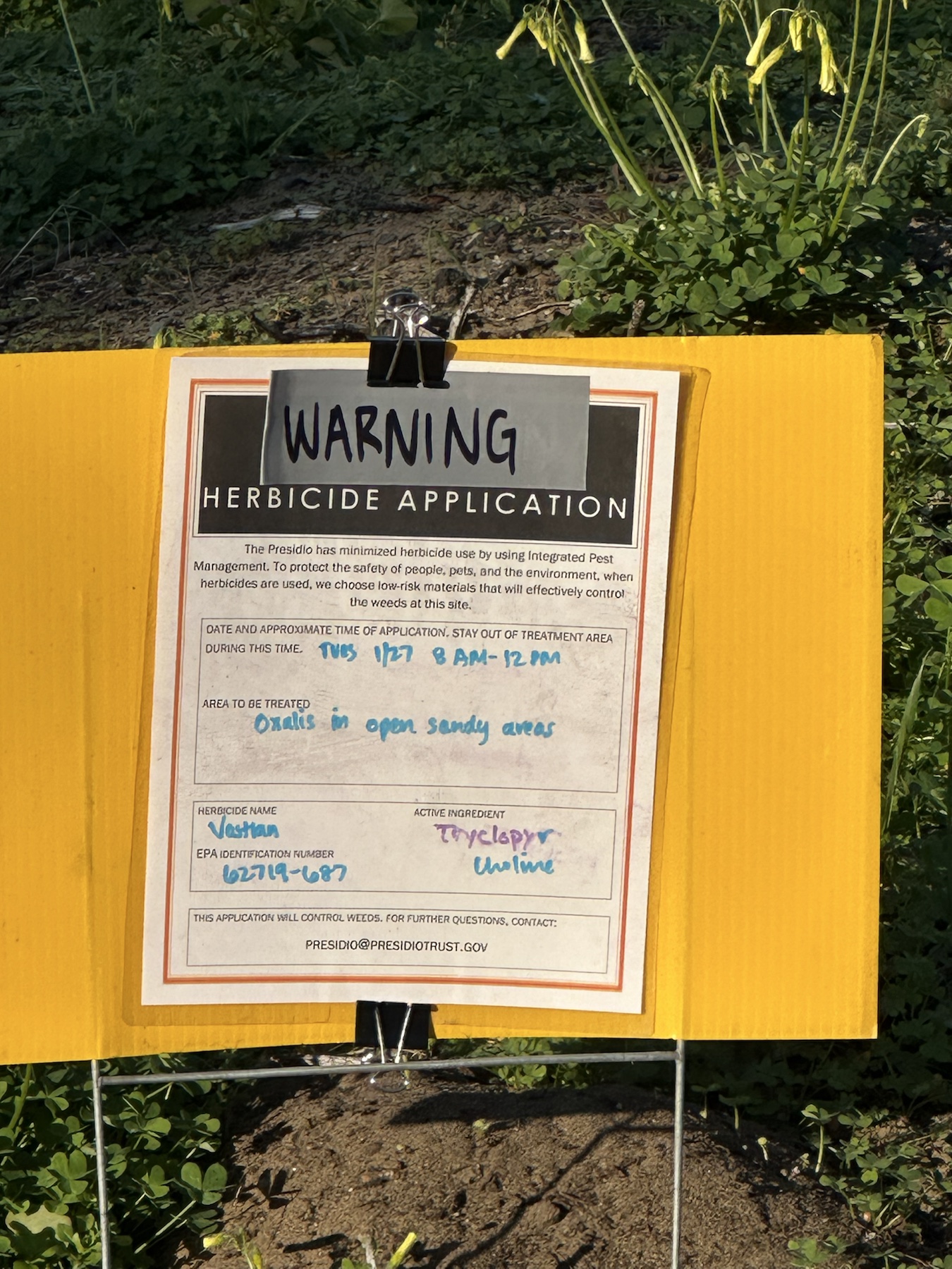 Close-up warning sign listing Vastlan for oxalis in open sandy areas